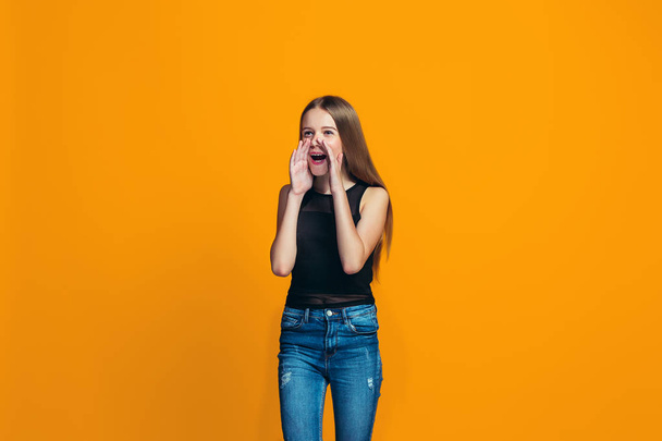 Isolated on yellow young casual teen girl shouting at studio - Foto, imagen