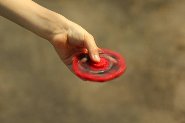 Gros plan de la main du garçon jouant avec le jouet rouge fidget spinner
 - Photo, image