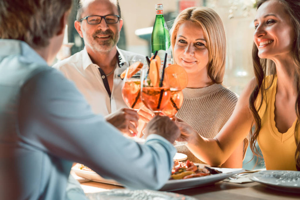 Giovani amici brindare con cocktail prima di mangiare frutti di mare in un ristorante
 - Foto, immagini