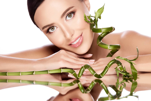 красива і природна молода жінка позує з рослинами зеленого бамбука на сірому фоні, концепція догляду за шкірою, гідратована шкіра
 - Фото, зображення