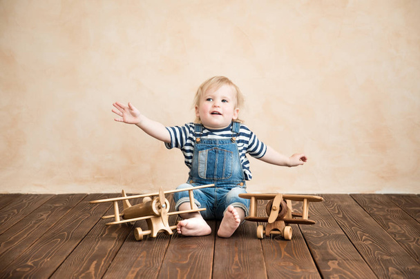 Happy child playing at home. Baby boy with toy airplane. Summer vacation and travel, dream and imagination concept - 写真・画像