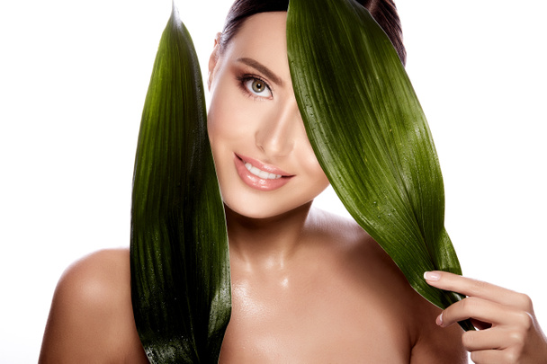 красивая и естественная молодая женщина позирует с зелеными листьями изолированы на белом фоне, концепция ухода за кожей, увлажненной кожи
 - Фото, изображение