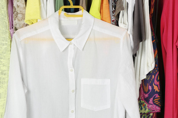 white transparent blouse on hanger in front of other female clothes in the closet - Φωτογραφία, εικόνα