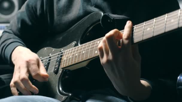 文字列でギタリストの指を閉じます。メンズは腕ロック ・ ミュージックの再生ソロです。男性ミュージシャンのエレク トリック ギターで演奏の手。スタジオでの美しい黒の背景。スローモーションをクローズ アップ - 映像、動画