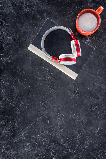 top view of book, headphones and red cup on grey tabletop - Foto, imagen