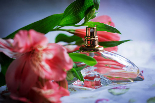 Parfumfles met bloemen op blauwe achtergrond - Foto, afbeelding
