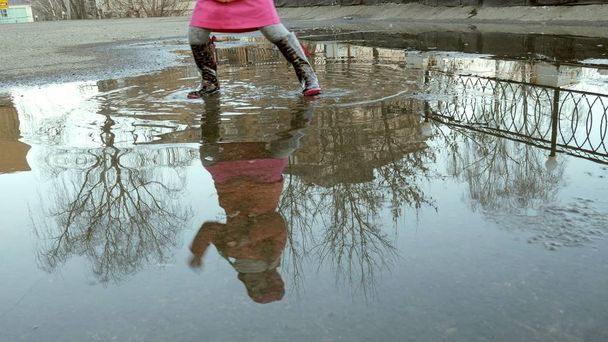 雨の後水たまりにジャンプ美しい少女 - 写真・画像
