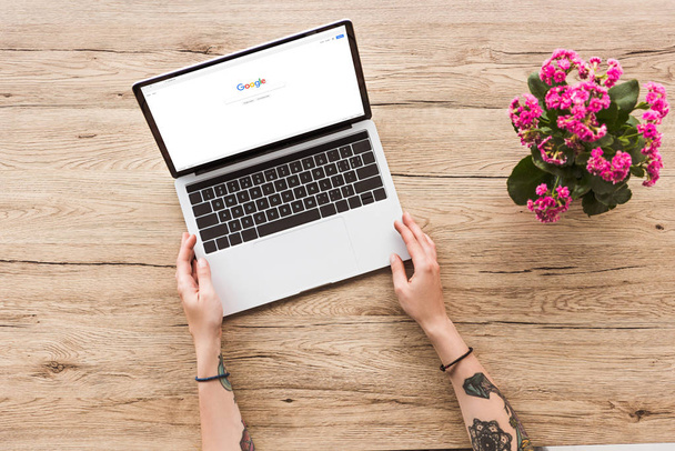 google logo ve kalanhoe bitki saksı ile dizüstü bilgisayar ile masa üstü kadına kısmi görünümünü - Fotoğraf, Görsel