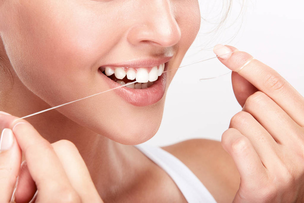 piękna kobieta uśmiechający się z białych zębów za pomocą nici dentystyczne, Stomatologia koncepcja - Zdjęcie, obraz