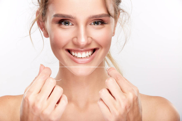 hermosa mujer sonriente con dientes blancos usando hilo dental, concepto de odontología
 - Foto, imagen