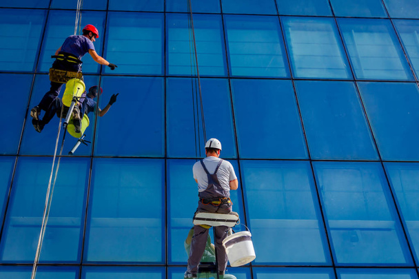 Endüstriyel dağcılar silikon kauçuk dönemde binanın cam cephe arasında için başvuruyorsanız. - Fotoğraf, Görsel
