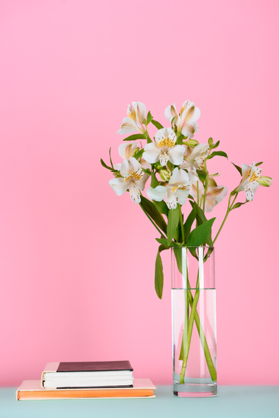 twee boeken en boeket van alstroemeria bloemen op tafel op roze - Foto, afbeelding