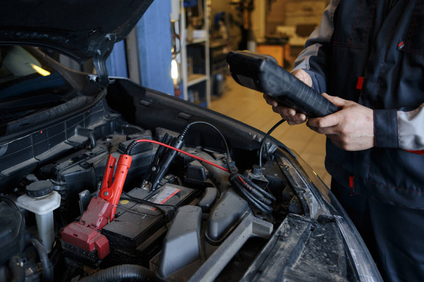 Battery charger and car in auto repair shop. - Photo, Image