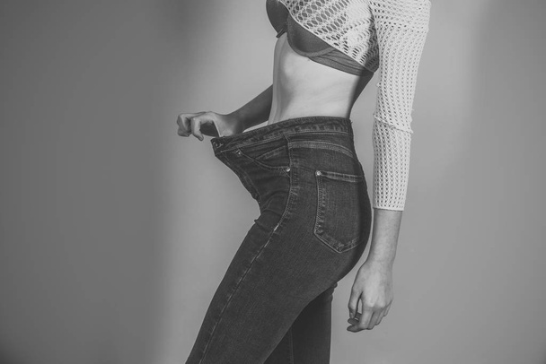Happy woman. Slim waist of young female in big jeans - 写真・画像