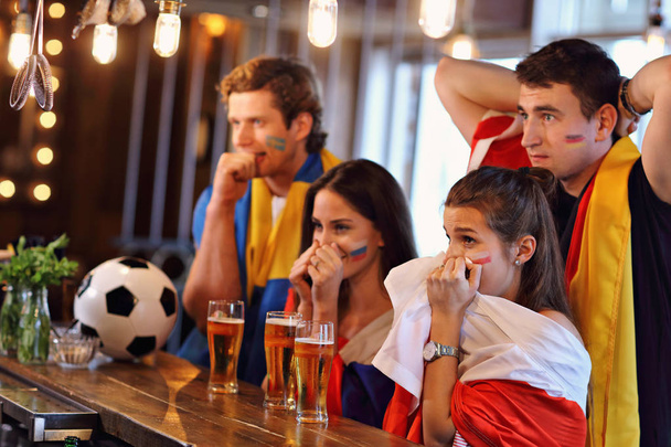 Grupo de amigos viendo el partido de fútbol en el pub
 - Foto, Imagen