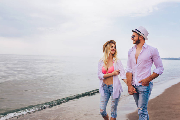 Romántica pareja joven divirtiéndose en la playa al atardecer
 - Foto, Imagen