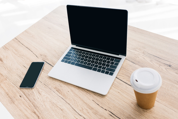 closeup view of smartphone with blank screen, laptop and coffee cup on wooden table  - Foto, Imagen