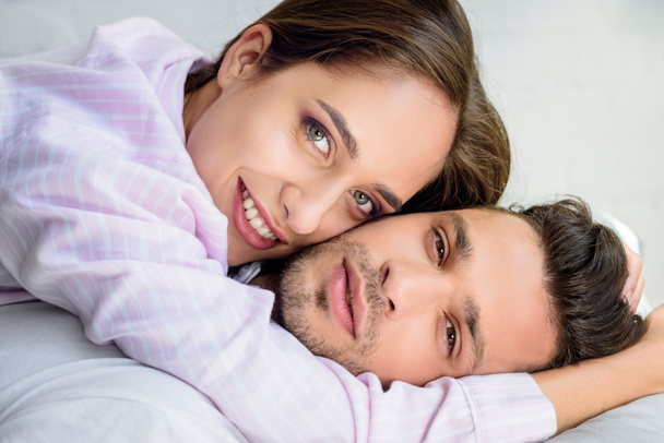 beautiful lovers hugging on bed and looking at camera - 写真・画像