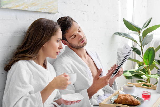 young couple with coffee for breakfast reading newspaper together - Photo, Image