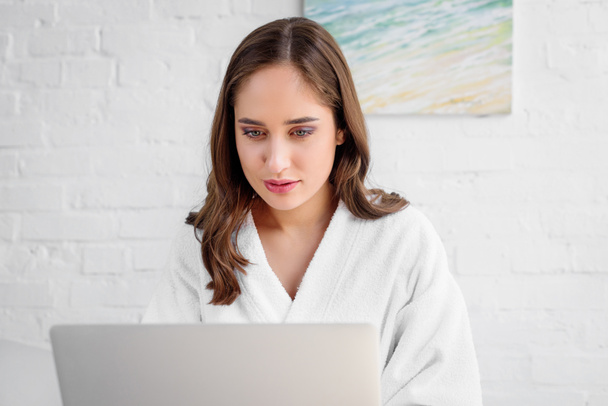 beautiful woman in bathrobe using laptop at home - Photo, Image