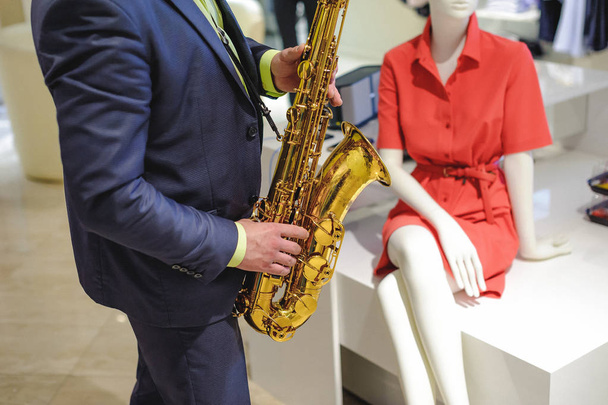 musician plays the saxophone performance at a concert in shopping center of women's clothing store on holiday - Foto, Imagem