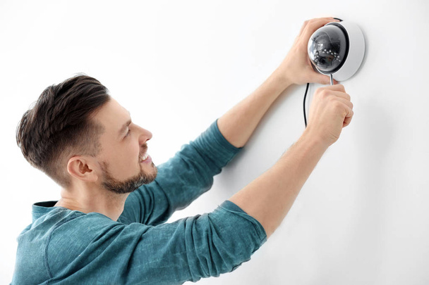 Technician installing CCTV camera on wall indoors - Фото, изображение