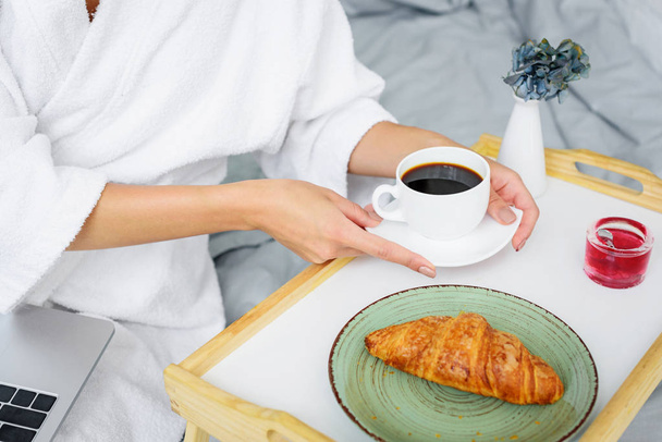 vágott nézet nő a fürdőköpeny tekintettel reggeli kávéval és croissant-t tartalmaz - Fotó, kép