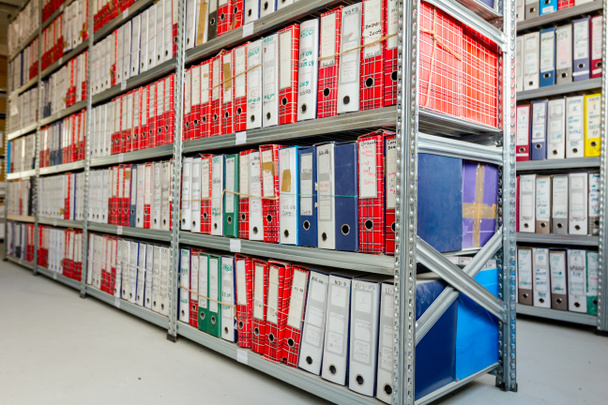 Des piles de fichiers et de documents placés dans des étagères avec des dossiers et des documents dans les archives des classeurs, dans la salle de stockage
. - Photo, image