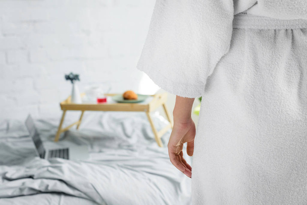 partial view of woman standing near bed with breakfast - Foto, afbeelding