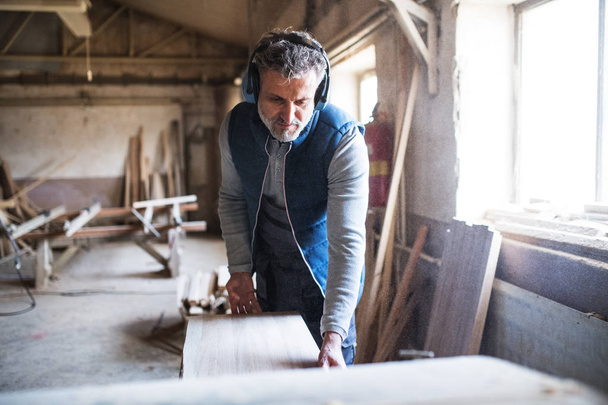 A man worker in the carpentry workshop, working with wood. - Φωτογραφία, εικόνα