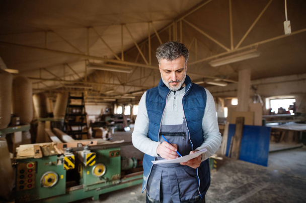 A man worker in the carpentry workshop, making plans. - Φωτογραφία, εικόνα