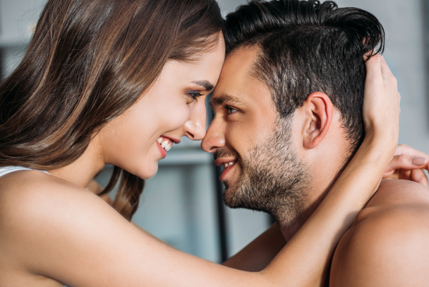 sensual smiling couple touching with foreheads and looking at each other at home - Foto, immagini