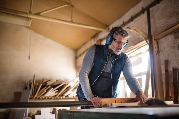 Um homem trabalhador na oficina de carpintaria, trabalhando com madeira
. - Foto, Imagem