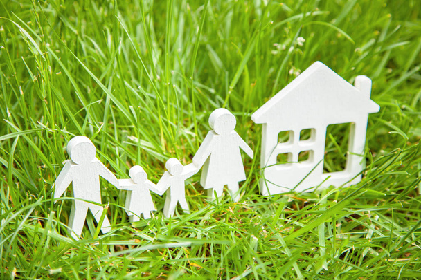 Familia de padre, madre, hijo e hija cerca de la casa en la hierba verde. Concepto es la casa ecológicamente limpia para la familia
. - Foto, imagen