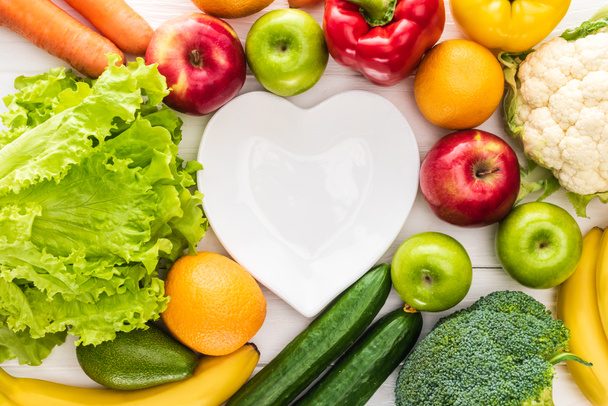 vista superior de frutas frescas com legumes e prato em forma de coração vazio na mesa de madeira
    - Foto, Imagem