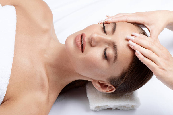young woman with perfect skin having facial massage, hands on face, skin care, spa procedure and relaxing concept  - 写真・画像
