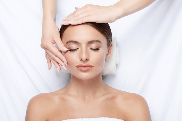 jonge vrouw met perfecte huid gezichtsmassage, met handen op gezicht, huidverzorging, spa procedure en ontspannende concept  - Foto, afbeelding