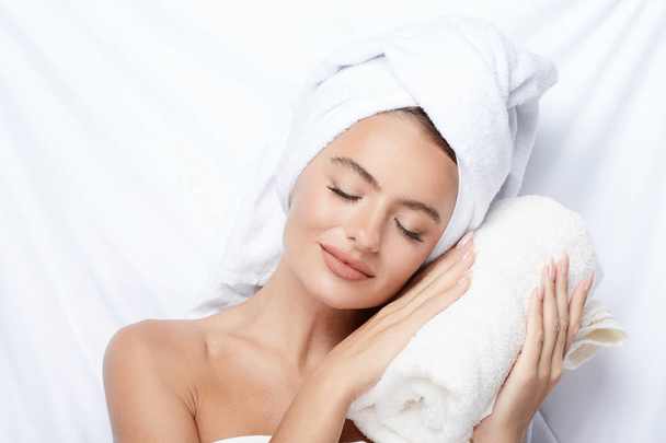 beautiful and natural young woman with perfect skin at white background, towel on head, beauty photo concept, skin care, spa concept, treatment, sleeping on towel - Zdjęcie, obraz
