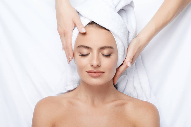 young woman with perfect skin having facial massage, hands on face, skin care, spa procedure and relaxing concept  - Фото, зображення