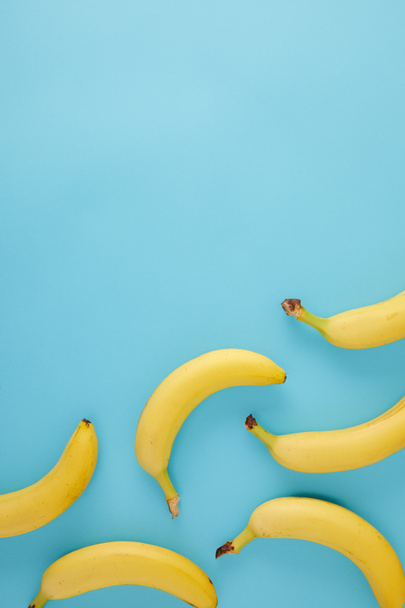 top view of arranged fresh bananas isolated on blue - Zdjęcie, obraz
