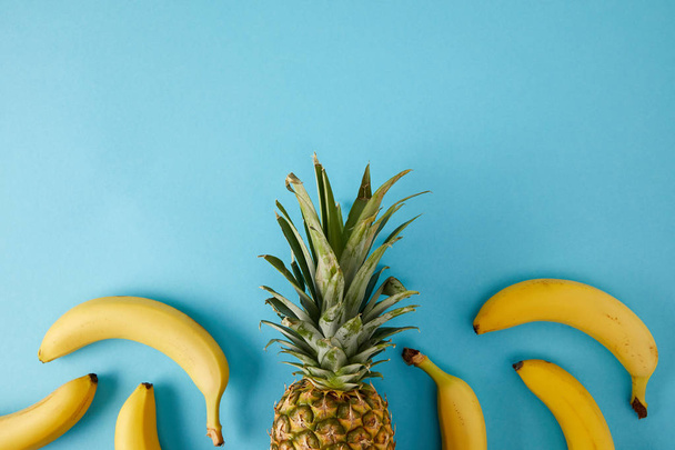 新鮮なバナナとパイナップルの青に分離されたフラット レイアウト - 写真・画像
