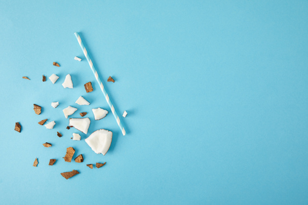 top view of arranged coconut pieces and straw isolated on blue - Photo, Image