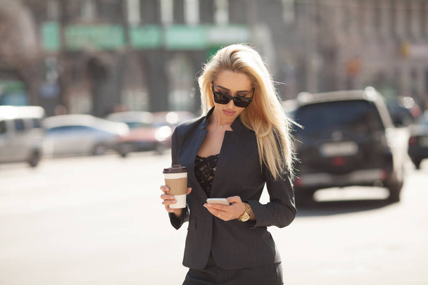 Successful businesswoman with cellphone while walking outdoor. City business woman working. - Фото, зображення