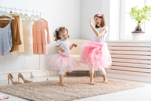 Happy girls dressing up at home. Funny lovely children are having fun in room. - 写真・画像