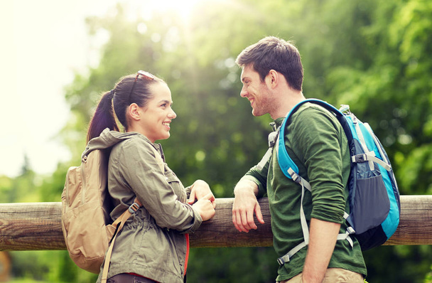 smiling couple with backpacks in nature - Foto, afbeelding