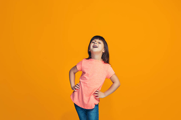 The happy teen girl standing and smiling against orange background. - Foto, Imagen