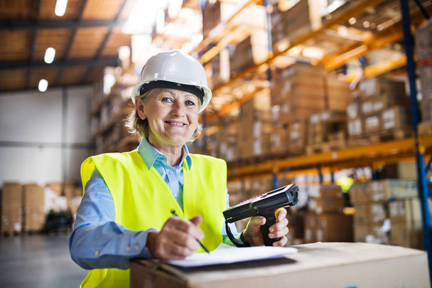 Senior warehouse woman worker with barcode scanner. - 写真・画像