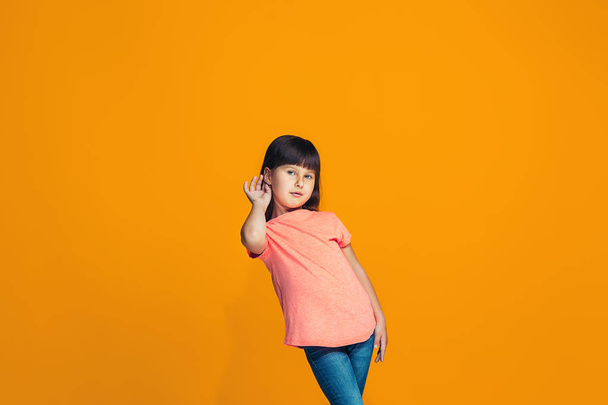 The young teen girl whispering a secret behind her hand over orange background - Foto, Imagen