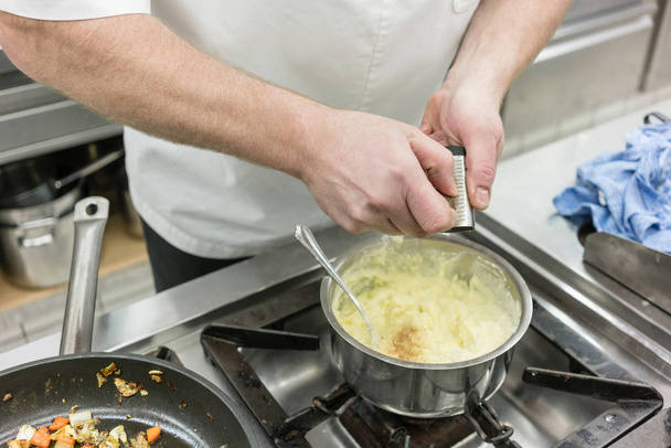 Koken in de keuken slijpen nootmuskaat in aardappelpuree - Foto, afbeelding