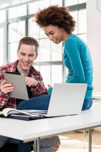 Два счастливых студента смотрят смешное видео на планшетном компьютере во время перерыва
 - Фото, изображение
